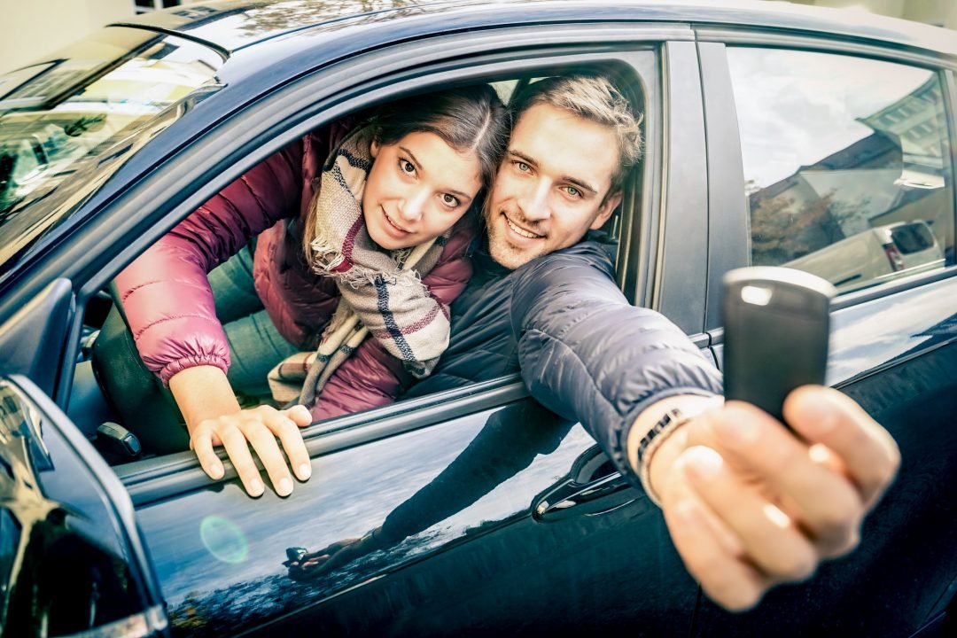 happy couple at car rent showing electronic key ready for the next road trip